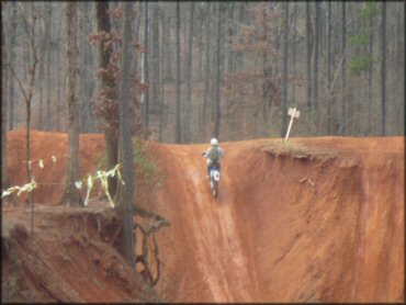 Man on dirt bike climbing steep hill climb.