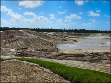 Side view of partially constructed motocross track surrounded by water puddles.