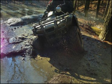 ATV and rider going through some deep mud.