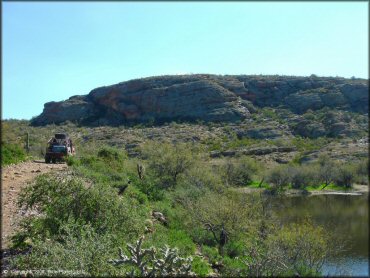 Rear view of Suzuki Samurai with sprare tire on the roof and cooler in the bed navigating rocky 4x4 trail.