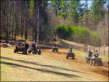 Group of ATV and UTV riders heading down a hardpacked woods trail.