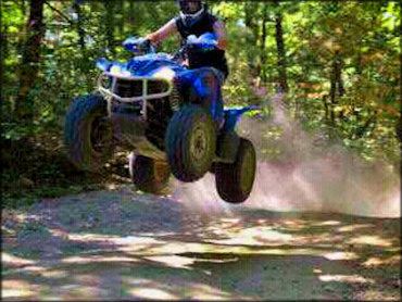 Young man on blue four wheeler catching some air.