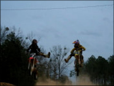 Two Riders on Motocross Bikes Jumping and Performing Tandem Freestyle Tricks