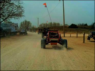 Group of dune buggies with orange whip flags going through RV campground.