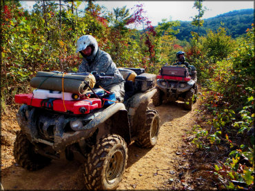 Yamaha Grizzly ATV with camping gear on smooth dirt trail.