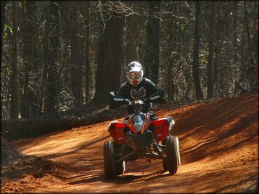 Honda four wheeler with MSR bark busters and UNI air filter decals navigating smooth ATV trail.