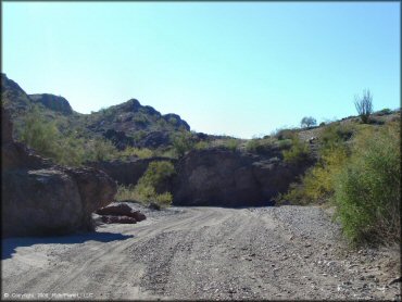 A section of sandy wash surrounded by rock boulders and desert scrub brush.