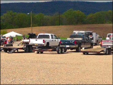 Ford F250 with flatbed trailer and other trucks and a KTM dirt bike parked in staging area.