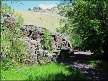 View of secluded picnic sites with mature shade trees surrounded by rock croppings.