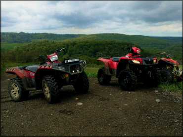 Three ATVs on a Hilltop with a Scenic Backdrop