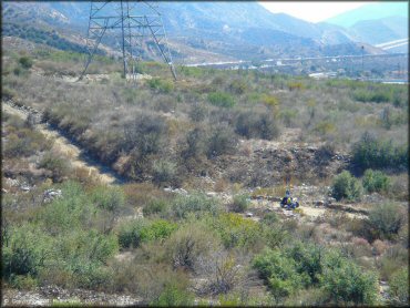 Mature woman on full sized ATV and young child on small ATV navigating 4x4 trail.