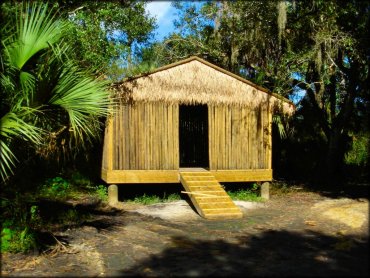 Tiki hut surrounded by palmettos, oak trees and spanish moss.