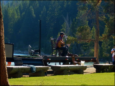 Musician singing and playing acoustic guitar with Redfish Lake in the background.