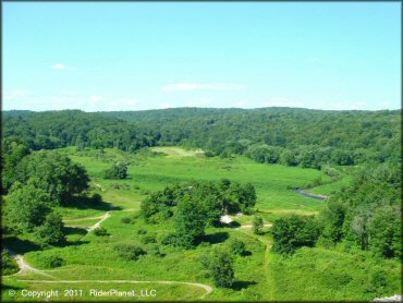 Scenic photo taken from main entrance road showing single track trails winding through grassy meadows and hardwood trees.