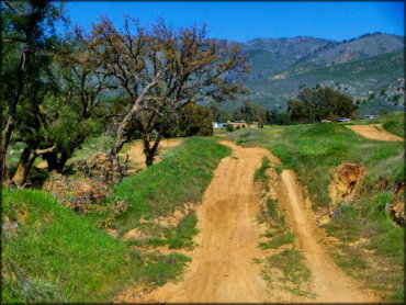 View of motocross track with some rugged sections and light uphill jumps.