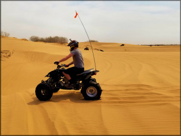 Rider wearing motorcycle hemet with flame patter sitting on ATV with paddle ties and orange whip flag attached.