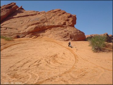 Man on Suzuki RM-250 riding up small sandy hill.