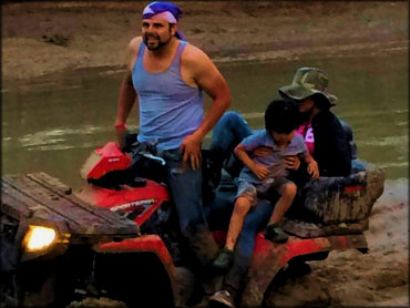 Polaris Sportsman with cargo box going through the mud.