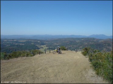 Scenic view of dirt bike rider looking out towards rolling hills and valleys.