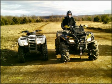 Two ATVs parked on a wide trail.