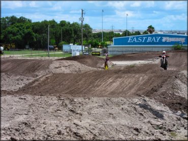 Man on Honda dirt bike catching a little air from a jump on track.