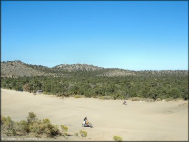 Suzuki and Honda dirt bikes riding around in flat open area.