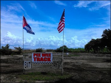 Entrance sign for peewee track with Cuban and American flags.