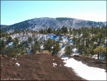 A scenic view of snow capped tall hill climb with pine trees.