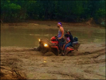 Polaris Sportsman with man, woman and child going through deep mud.