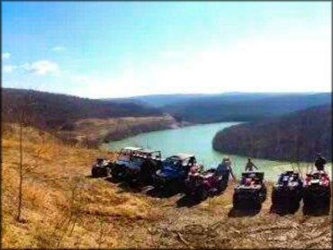 Side view of group photo of three UTVs and four ATVs parked next to each other with Potomac River in the back.