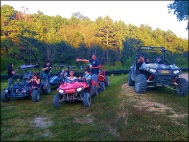 Two Polaris UTVs and two go karts parked on flat, grassy area.