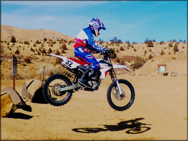 Motorcycle rider on a new Yamaha 250cc dirt bike catches air over a jump in near the trailhead of Rice Canyon.