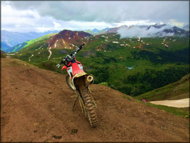 A Honda CRF 230cc dirt bike on the trail overlooking a lush green valley.