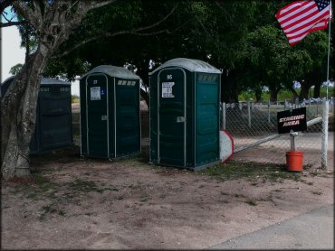 Chemical toilets under shade trees at main staging area.