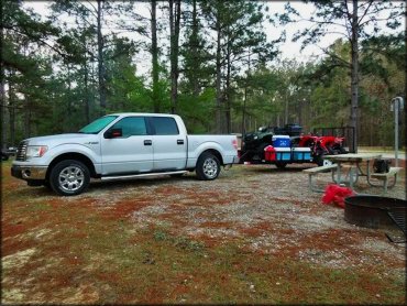 Full sized truck attached to utility trailer carrying three four wheelers, coolers and camping supplies.