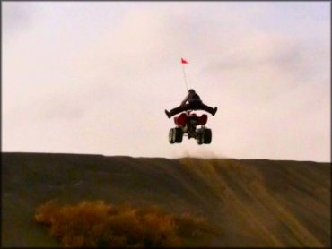 Honda ATV with rider jumping a big dune.