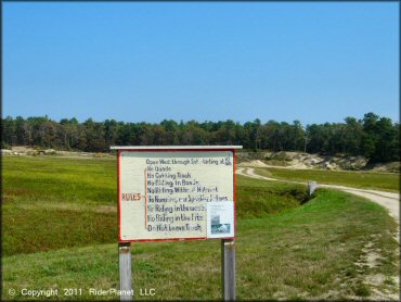 Main entrance sign with track rules and honor box.