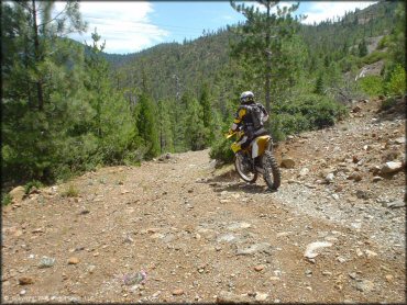 Suzuki RM250 dirt bike navigating a rocky 4x4 trail.