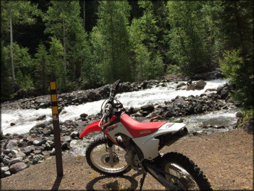 Honda CRF motor bike parked next to a trail marker.
