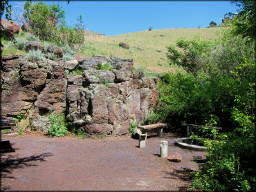 Scenic view of picnic area surrounded by rock wall and grassy trees.