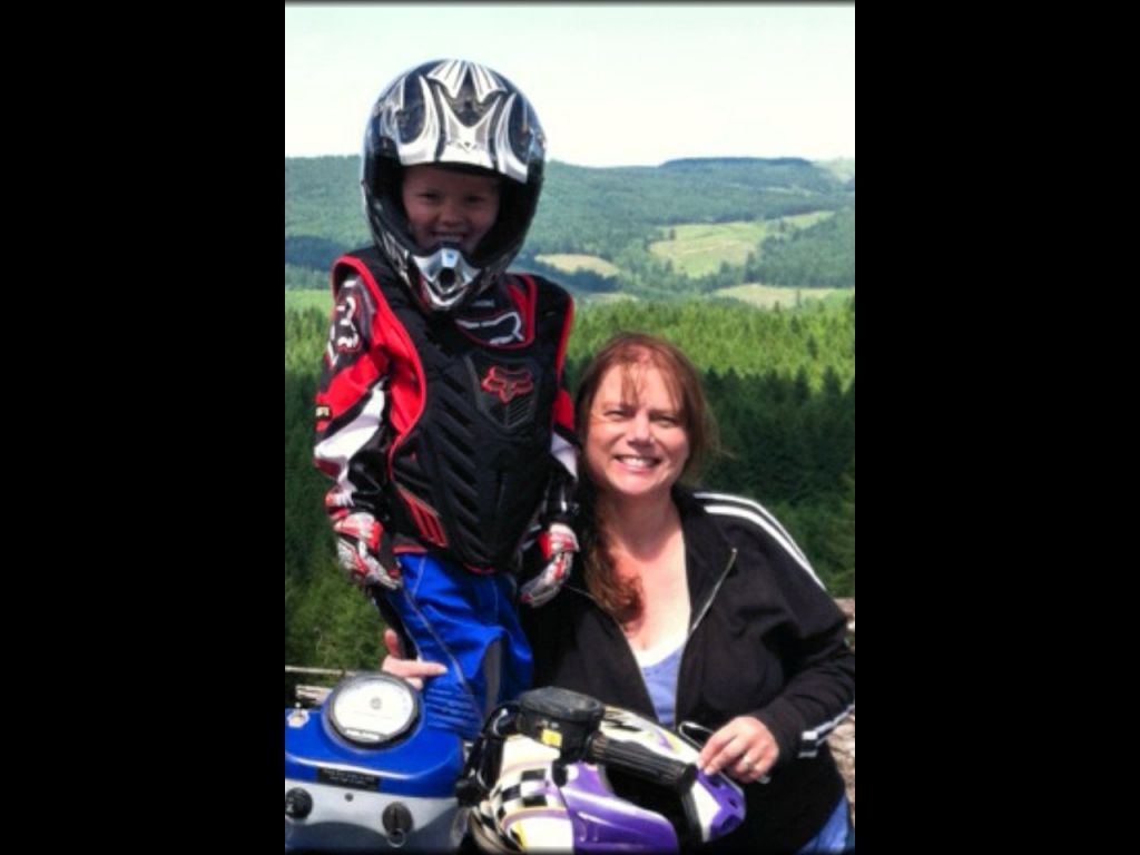 Woman standing next to young child wearing Fox Racing motocross jersey, gloves and chest protector.