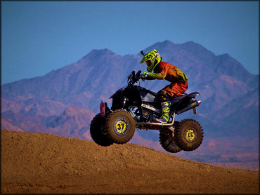 An ATV Rider Jumping With Mountains in the Background