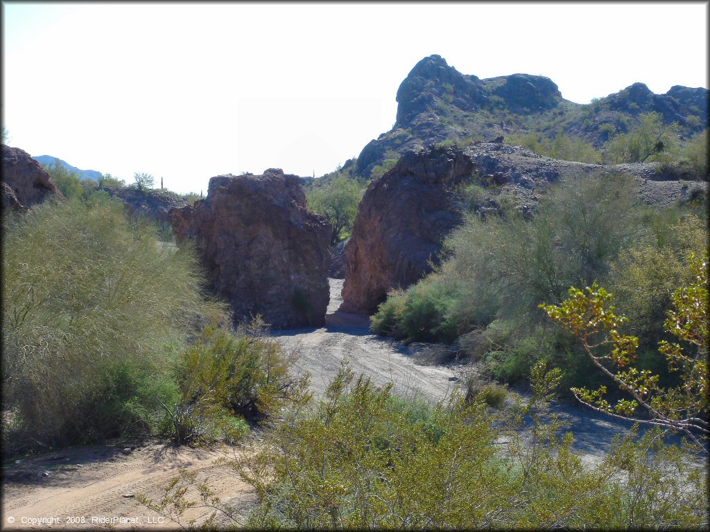 Photo of a sand wash cutting through a narrow channel of large rugged boulders.