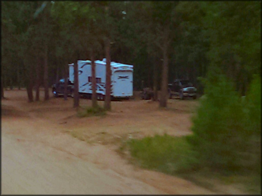 Toy hauler attached to full sized pickup truck parked in primitive campsite.