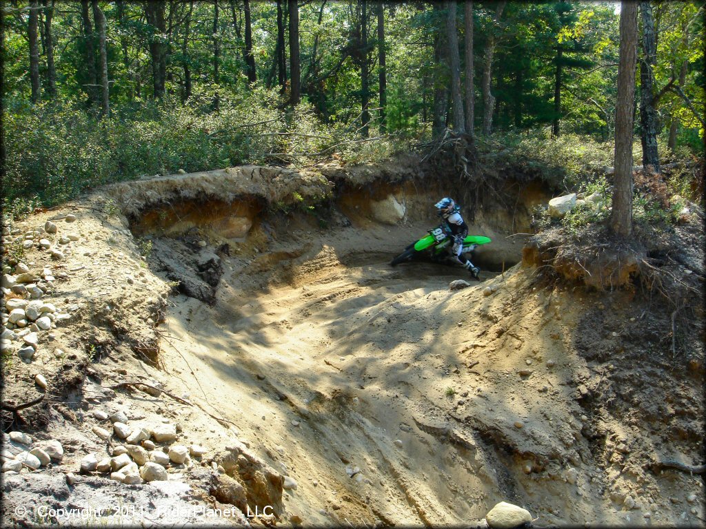 KX dirt bike going through sandy turn on motocross track.