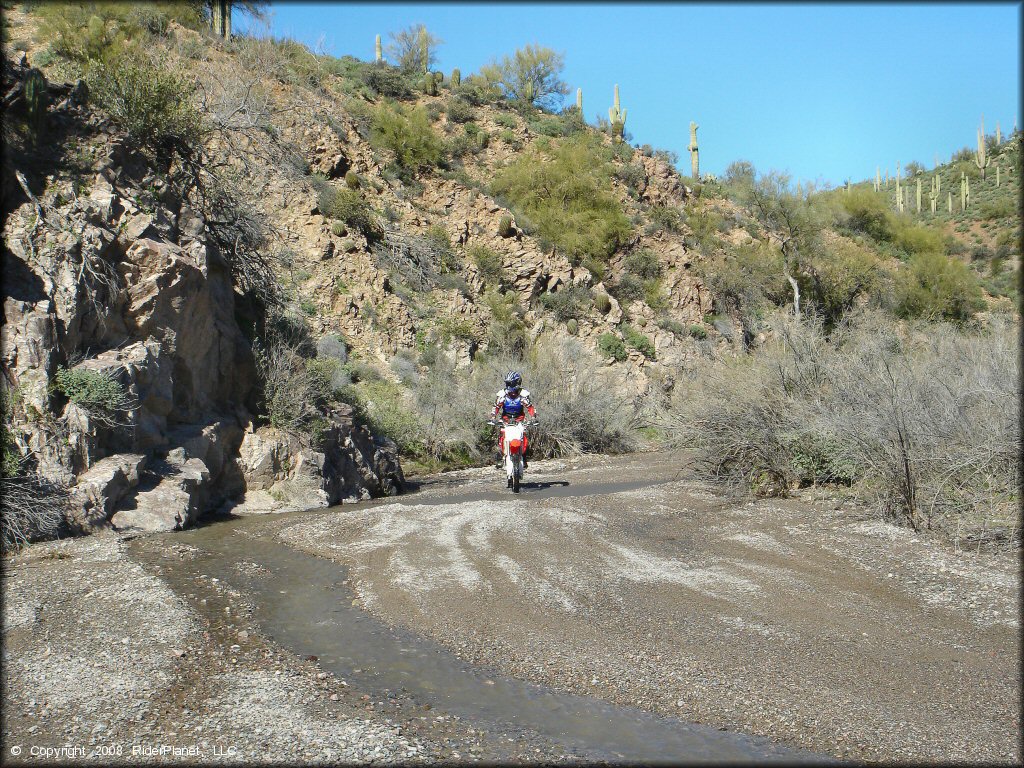 Dirt bike going through gravel stream wash.