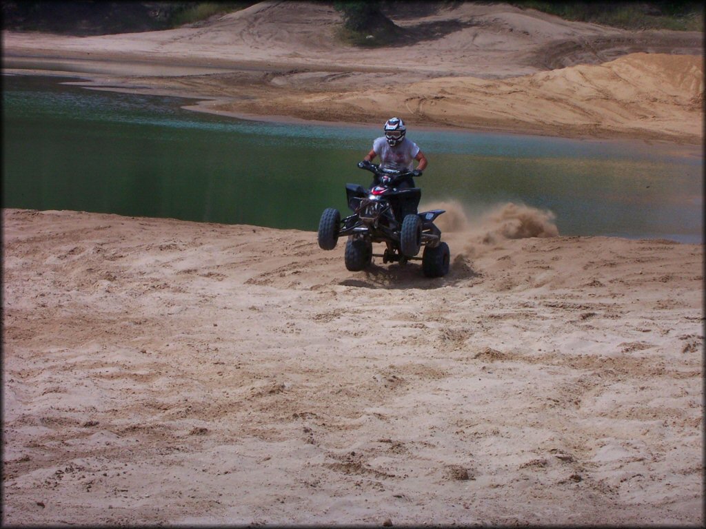 Man on ATV doing a wheelie in the sand.