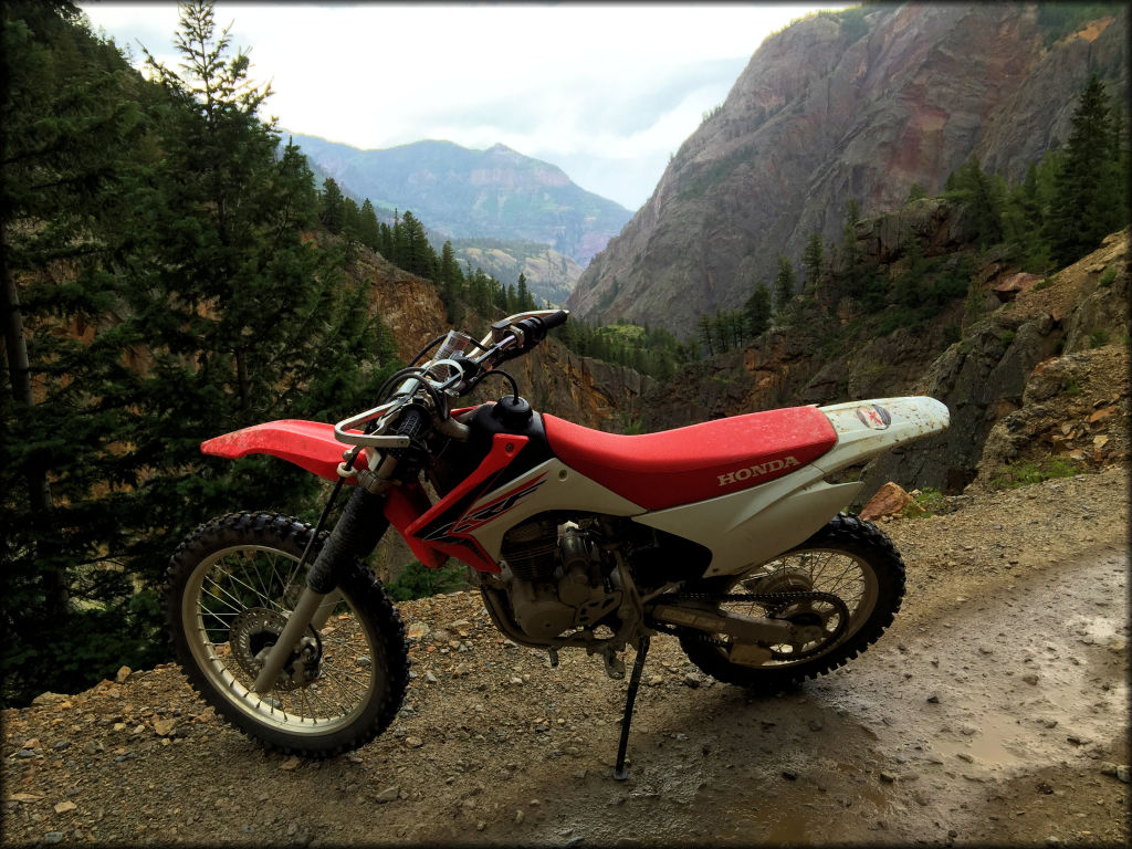 A Honda CRF 230 parked near the edge of a steep cliff.