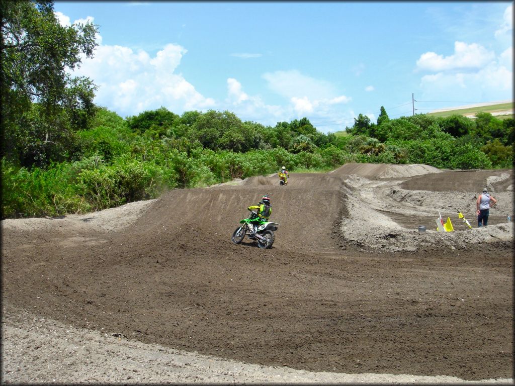 Kawasaki dirt bike going up small jump on motocross track.