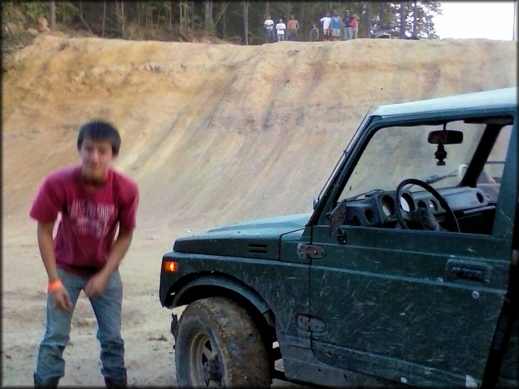 Dark green Jeep parked at in sandy play area.